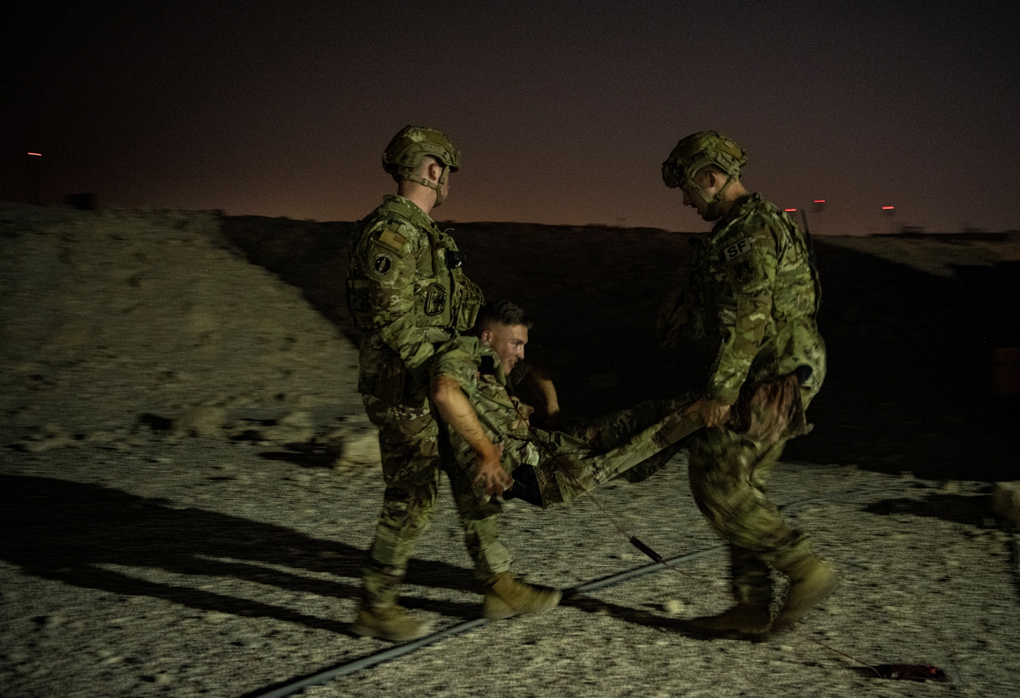 Photo of U.S. Air Force security forces members carrying a simulated casualty during a training scenario.