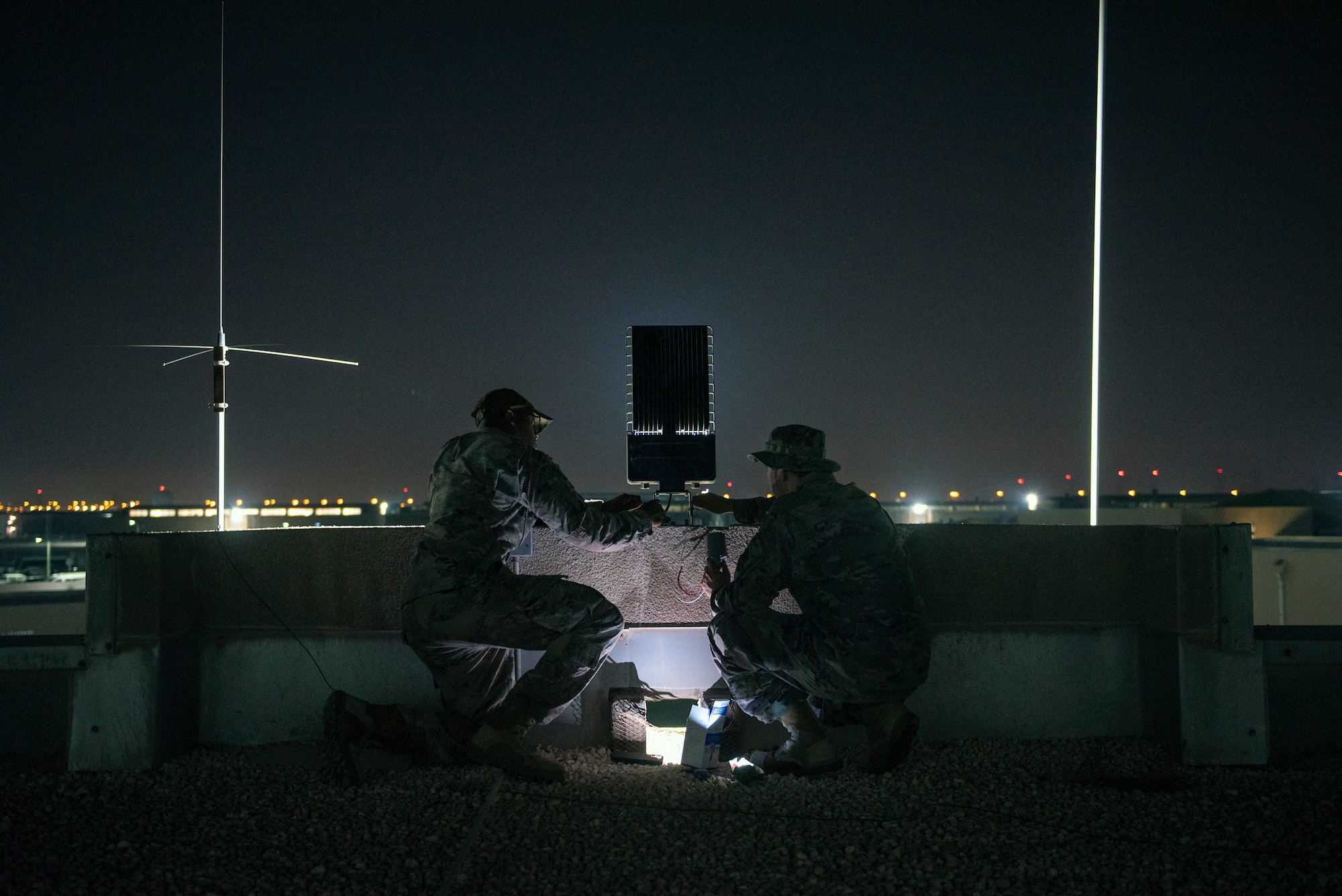 Airmen install a 300 watt LED flood light fixture