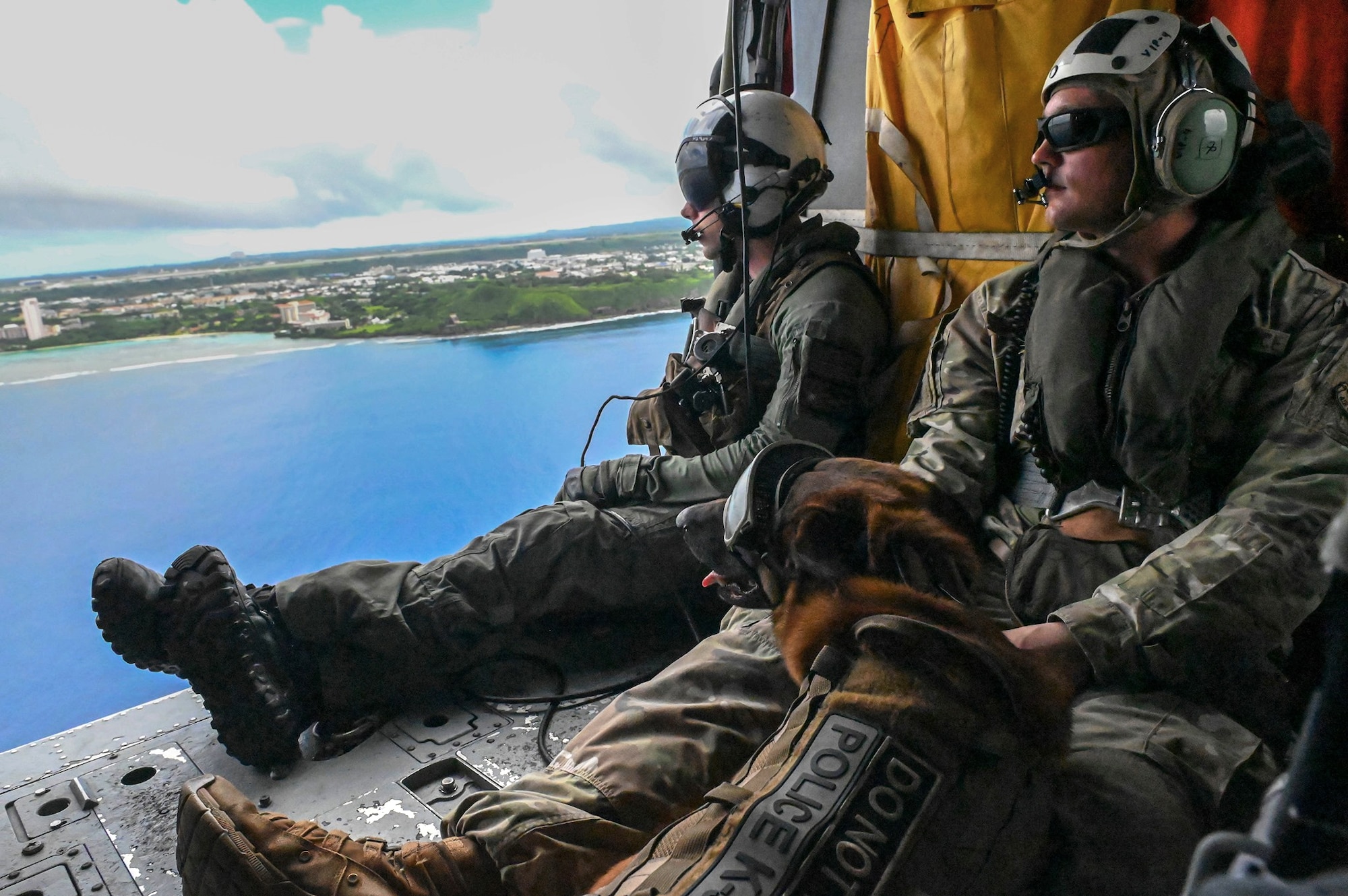 Airmen and working dog sits on floor of helicopter