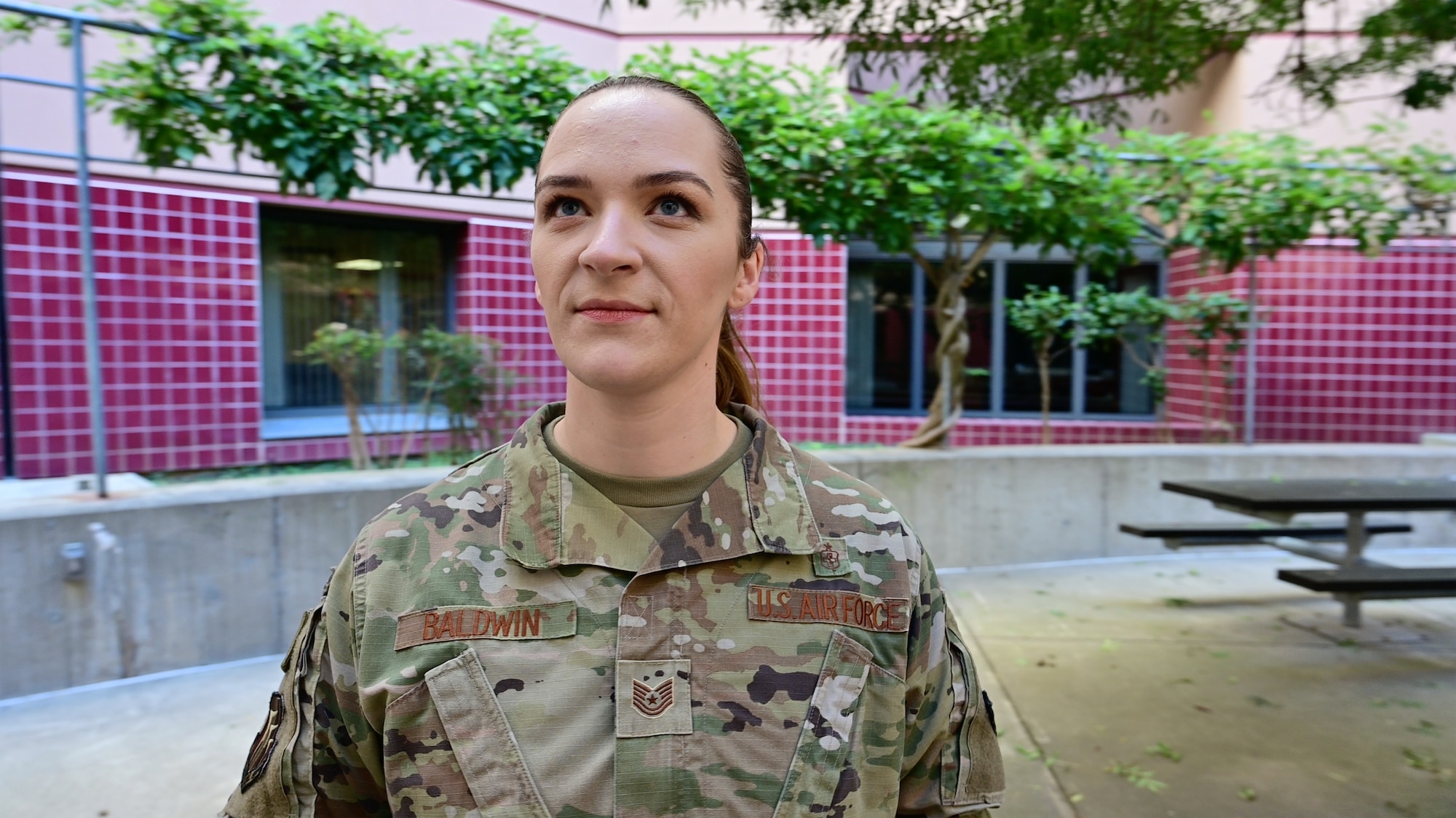 A woman in military uniform stands and looks towards the sky.