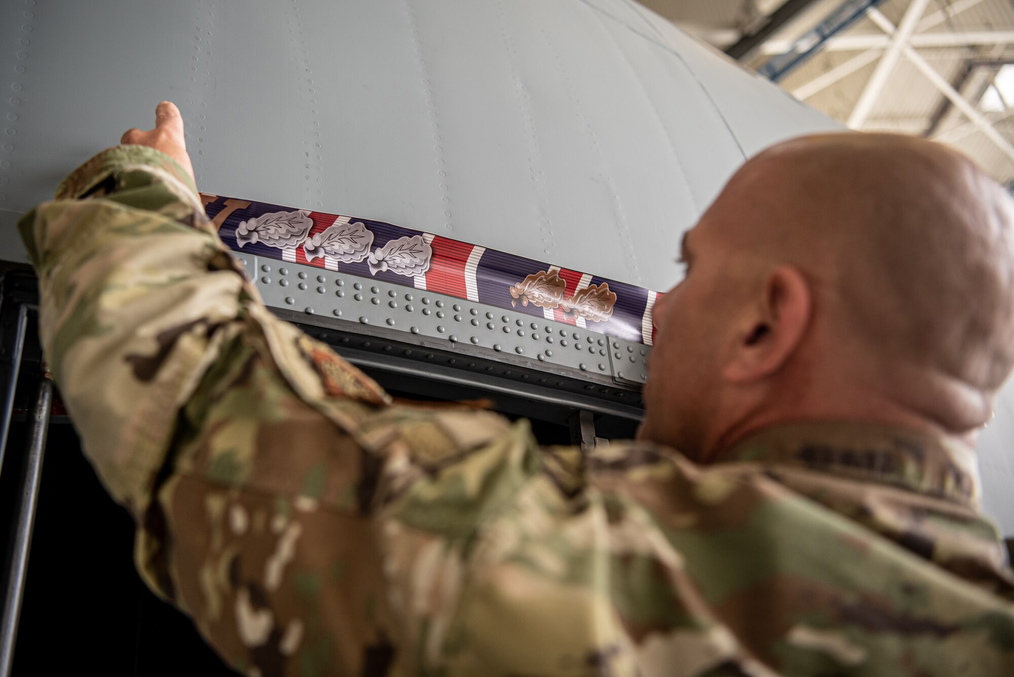 Chief Master Sgt. Tim Kenney, aircraft structural repair shop chief for the 123rd Maintenance Group, applies a decal depicting the 123rd Airlift Wing’s 19 Outstanding Unit Awards above the crew door of one of the Kentucky Air National Guard’s newly acquired C-130J Super Hercules aircraft at Channel Islands Air Guard Station in Port Hueneme, Calif., Nov. 3, 2021. The new aircraft is replacing the C-130H Hercules, which has been in service to the Kentucky Air National Guard since 1992. (U.S. Air National Guard photo by Tech. Sgt. Joshua Horton)