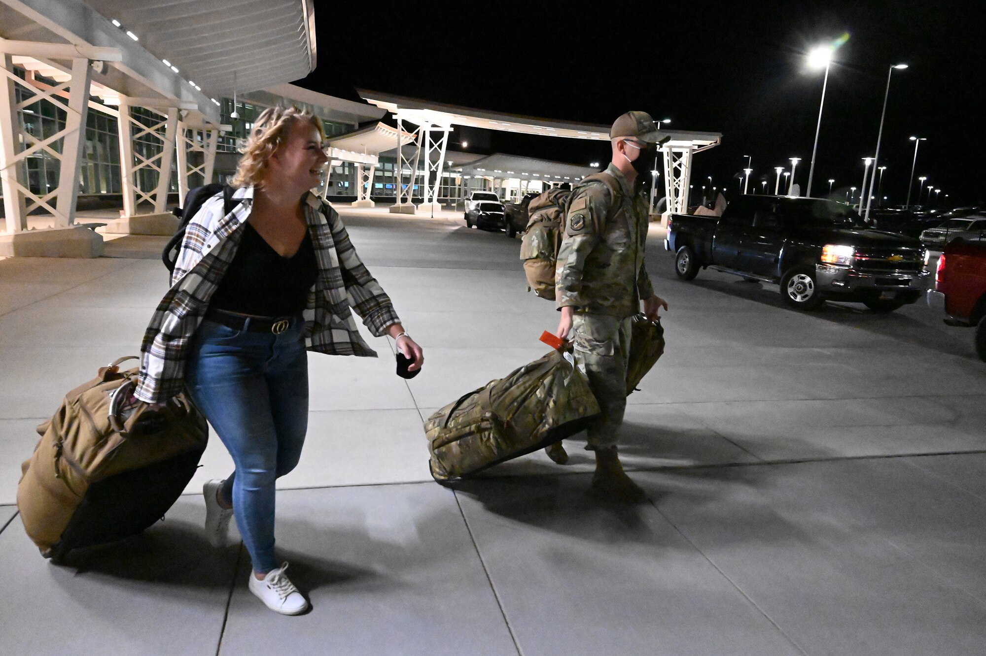 Two military member in uniform pick up their travel luggage from baggage claim at the Minot International Airport, Minot, N.D., Nov. 4, 2021.