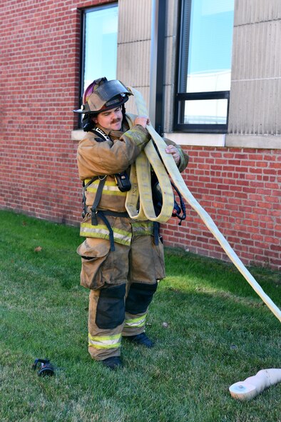 Tech. Sgt. Matthew Annis, firefighter with the 104th Civil Engineer Squadron, rolls up a hose during a midpoint inspection on November 5, 2021 at Barnes Air National Guard Base, Massachusetts. Midpoint inspections are conducted to evaluate the wing’s capabilities to respond to threats in a contested, degraded, and operationally limited environment. (U.S. Air National Guard photo by Senior Airman Camille Lienau)