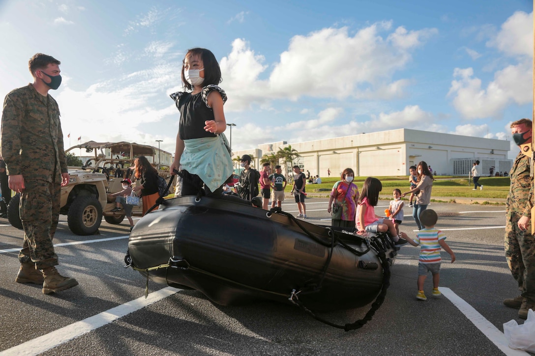 CAMP SCHWAB, OKINAWA, Japan – Okinawa residents play on a Combat Rubber Raiding Craft static display during an open-gate festival at Camp Schwab, Okinawa, Japan, Nov. 7, 2021. The festival was the first open-gate event hosted on Marine Corps installations in Okinawa in over a year due to COVID-19. (U.S. Marine Corps Photo by Matthew Manning)
