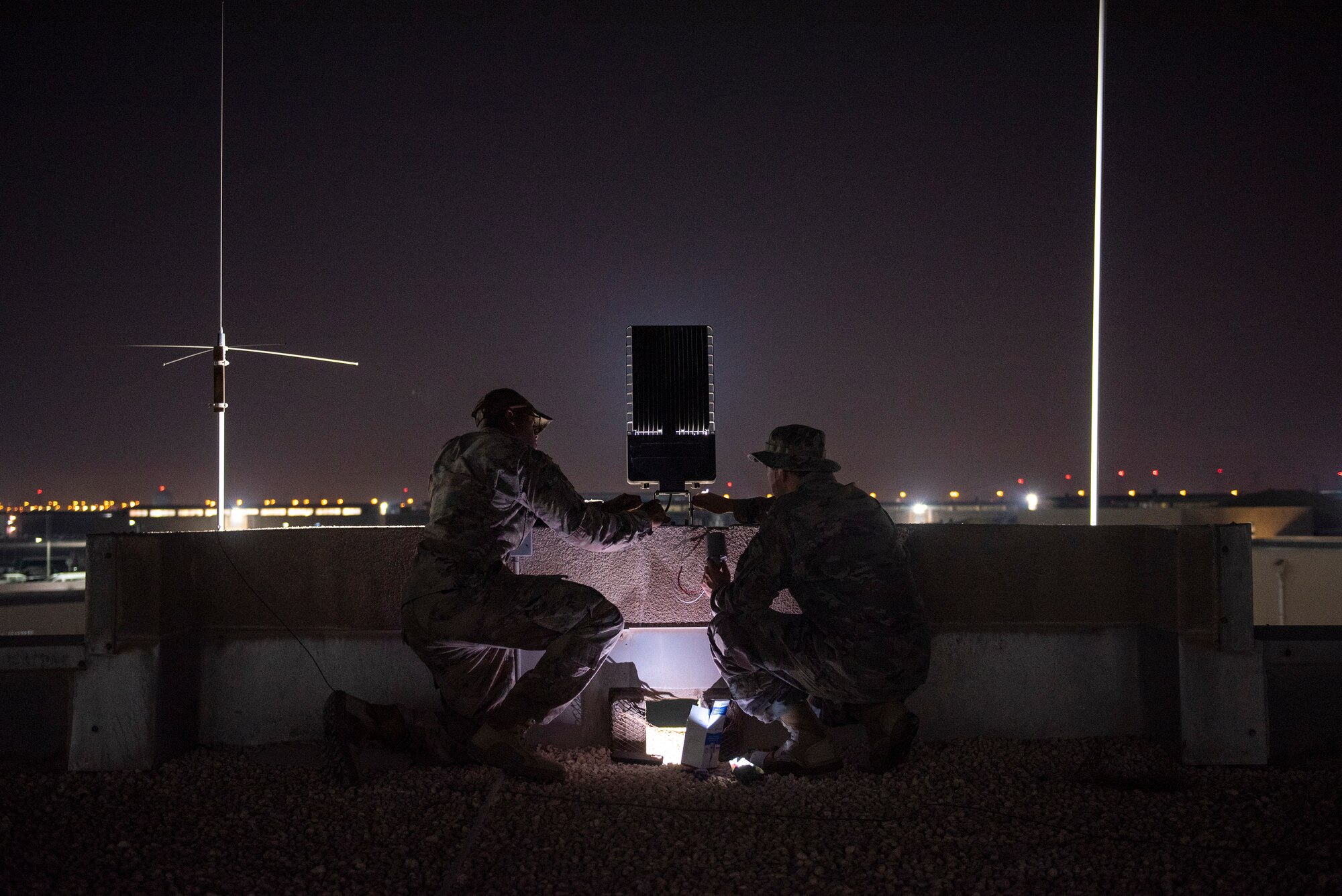 photo of two U.S. Air Force Airmen setting up LED lights outside in the dark