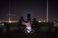 photo of two U.S. Air Force Airmen setting up LED lights outside in the dark