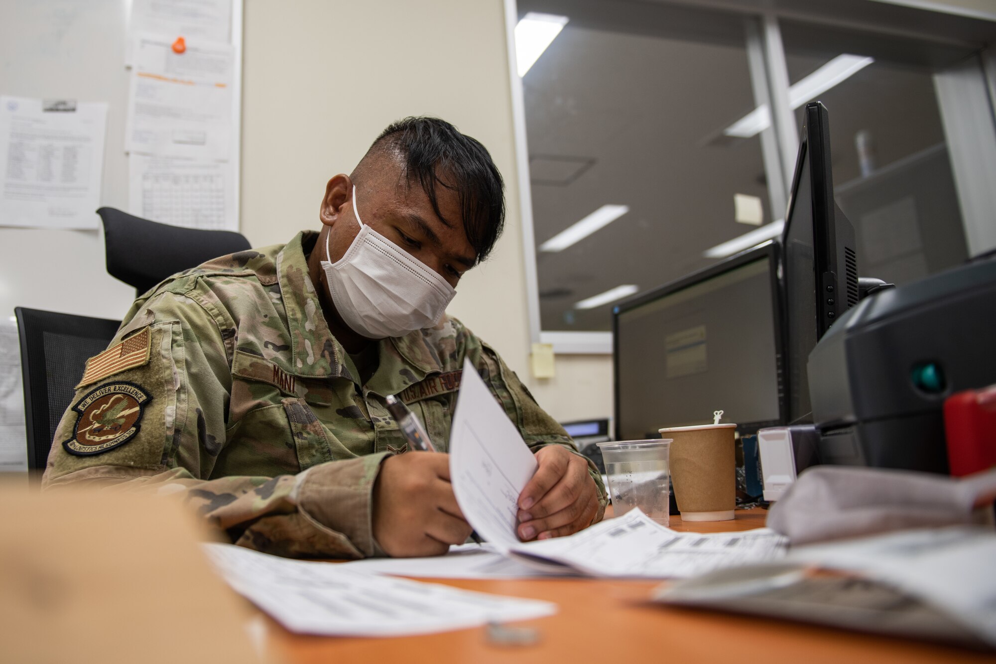 An Airman signs off on papers at his desk