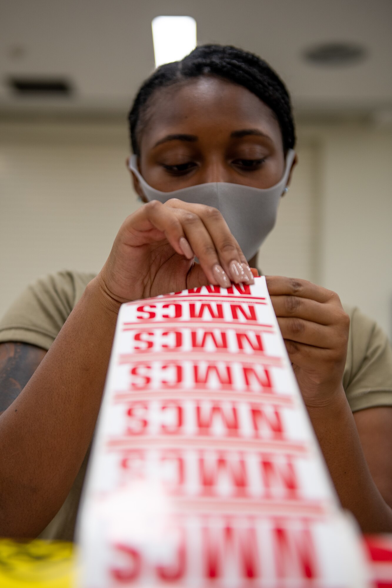 An Airman peels off a sticker from a roll of stickers