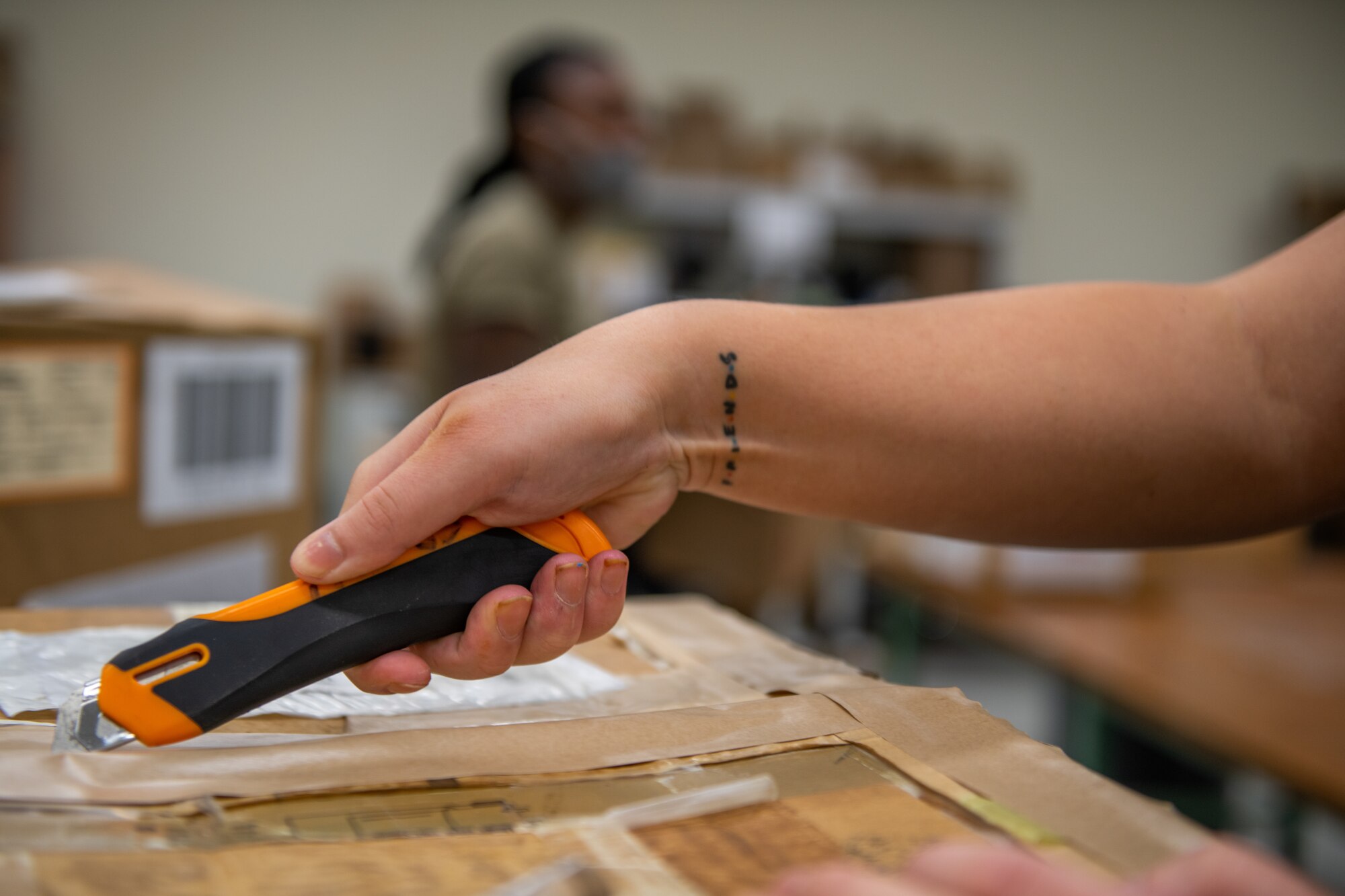 A hand holding a knife opens up a package