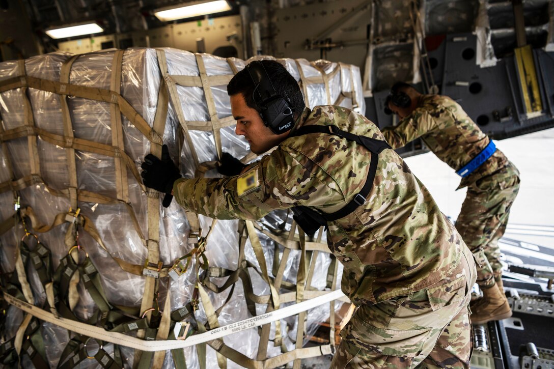 Two airmen move a pallet loaded with COVID-19 test kits and monitors.