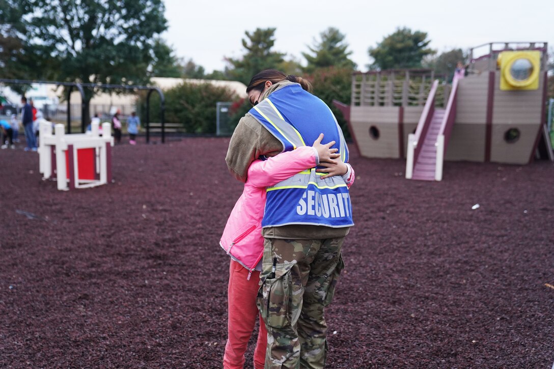 A service member hugs an Afghan child.