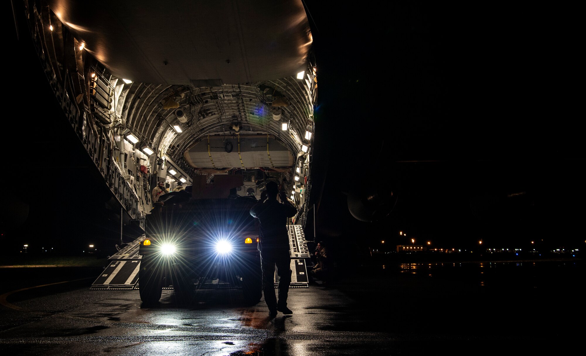 U.S. Air Force Senior Airman Keoni Gibson, 8th Airlift Squadron loadmaster, marshals a U.S. Army HUMVEE onto a C-17 Globemaster III during Exercise Rainier War 21B at Joint Base Lewis-McChord, Washington, Nov. 6, 2021. Rainier War is a semi-annual, large readiness exercise led by 62nd Airlift Wing, designed to train aircrews under realistic scenarios that support a full spectrum readiness operations against modern threats and replicate today’s contingency operations. (U.S. Air Force photo by Staff Sgt. Tryphena Mayhugh)
