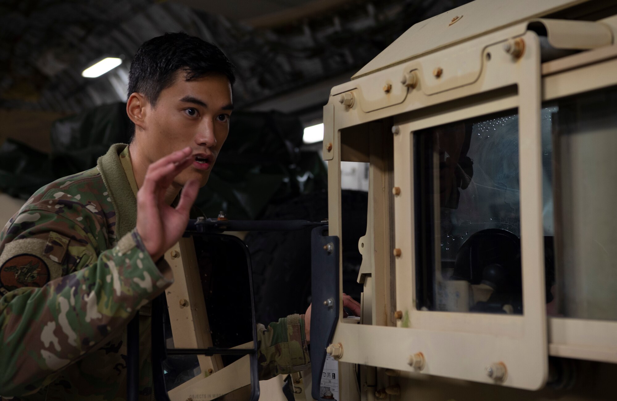 U.S. Air Force Senior Airman Keoni Gibson, 8th Airlift Squadron loadmaster, marshals a U.S. Army HUMVEE onto a C-17 Globemaster III during Exercise Rainier War 21B at Joint Base Lewis-McChord, Washington, Nov. 6, 2021. Rainier War 21B exercises and evaluates the wing’s ability to employ the force and their ability to perform during wartime and/or contingency taskings in a high-intensity, wartime contested, degraded and operationally limited environment while supporting the contingency operations against a near-peer adversary in the U.S. Indo-Pacific Command area of responsibility. (U.S. Air Force photo by Staff Sgt. Tryphena Mayhugh)