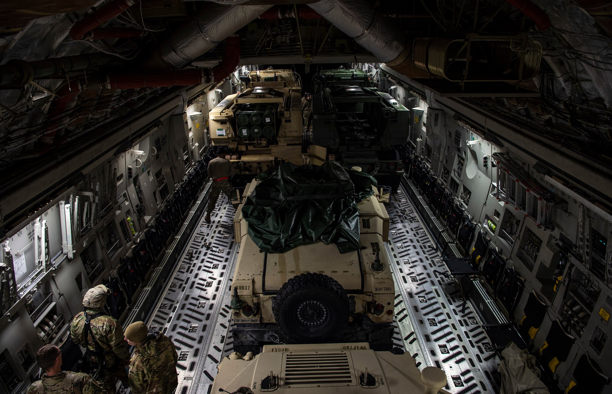 Two U.S. Army M142 High Mobility Artillery Rocket System (HIMARS) and two U.S. Army HUMVEEs sit inside a C-17 Globemaster III for a HIMARS Rapid Infiltration (HIRAIN) joint operation during Exercise Rainier War 21B at Joint Base Lewis-McChord, Washington, Nov. 6, 2021. Rainier War is a semi-annual, large readiness exercise led by 62nd Airlift Wing, designed to train aircrews under realistic scenarios that support a full spectrum readiness operations against modern threats and replicate today’s contingency operations. (U.S. Air Force photo by Staff Sgt. Tryphena Mayhugh)