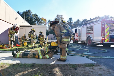 Senior Airman Dominic Isidro and Tech. Sgt. Matthew Annis, firefighters with the 104th Civil Engineer Squadron, drag Senior Airman Thomas Ruffo, firefighter with the 104CES, out of a simulated burning building during a midpoint readiness exercise Nov. 6, 2021, at Barnes Air National Guard Base, Massachusetts. Midpoint inspections evaluate the wing’s capabilities to respond to threats in a contested, degraded and operationally limited environment.