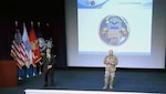 a civilian and military leader stand on a stage