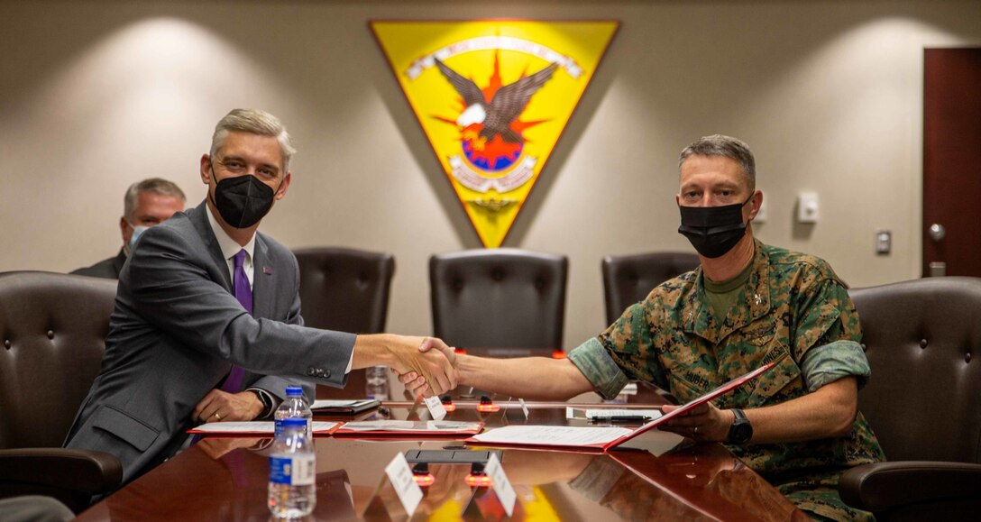 Dr. Philip Rogers, the chancellor of East Carolina University, and U.S. Marine Corps Col. Mikel Huber, commanding officer of Marine Corps Air Station  Cherry Point, shake hands after signing a memorandum of understanding , signifying a future partnership between the installation and ECU at the Christian F. Schilt Building at MCAS Cherry Point, North Carolina, Nov. 5, 2021. ECU will offer in-person classes for two separate degree programs, industrial distribution and logistics, and industrial technology.