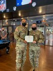 Two male soldiers holding up an award.