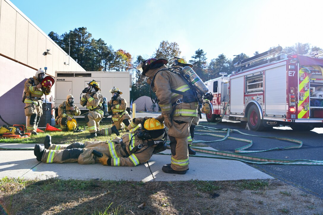 Senior Airman Dominic Isidro and Tech. Sgt. Matthew Annis, firefighters with the 104th Civil Engineer Squadron, drag Senior Airman Thomas Ruffo, firefighter with the 104CES, out of a simulated burning building during a midpoint readiness exercise November 6, 2021, at Barnes Air National Guard Base, Massachusetts. Midpoint inspections are conducted to evaluate the wing’s capabilities to respond to threats in a contested, degraded, and operationally limited environment. (U.S. Air National Guard photo by Staff Sgt. Hanna Smith)