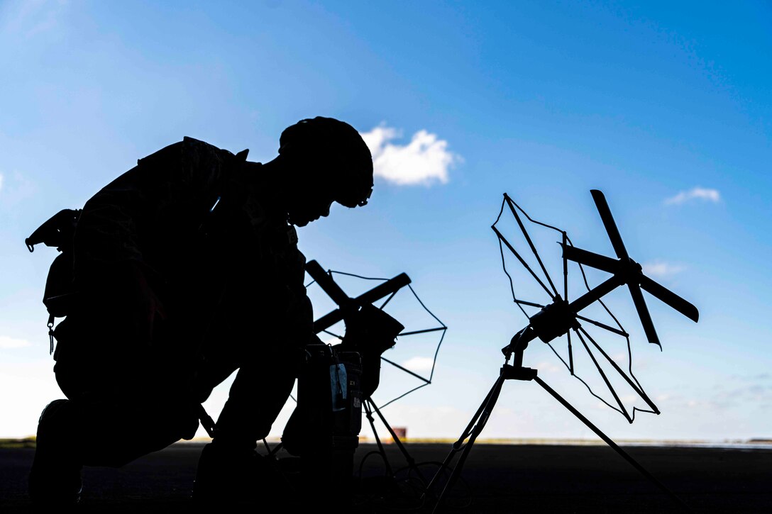 A Marine shown in silhouette sets up an antenna.