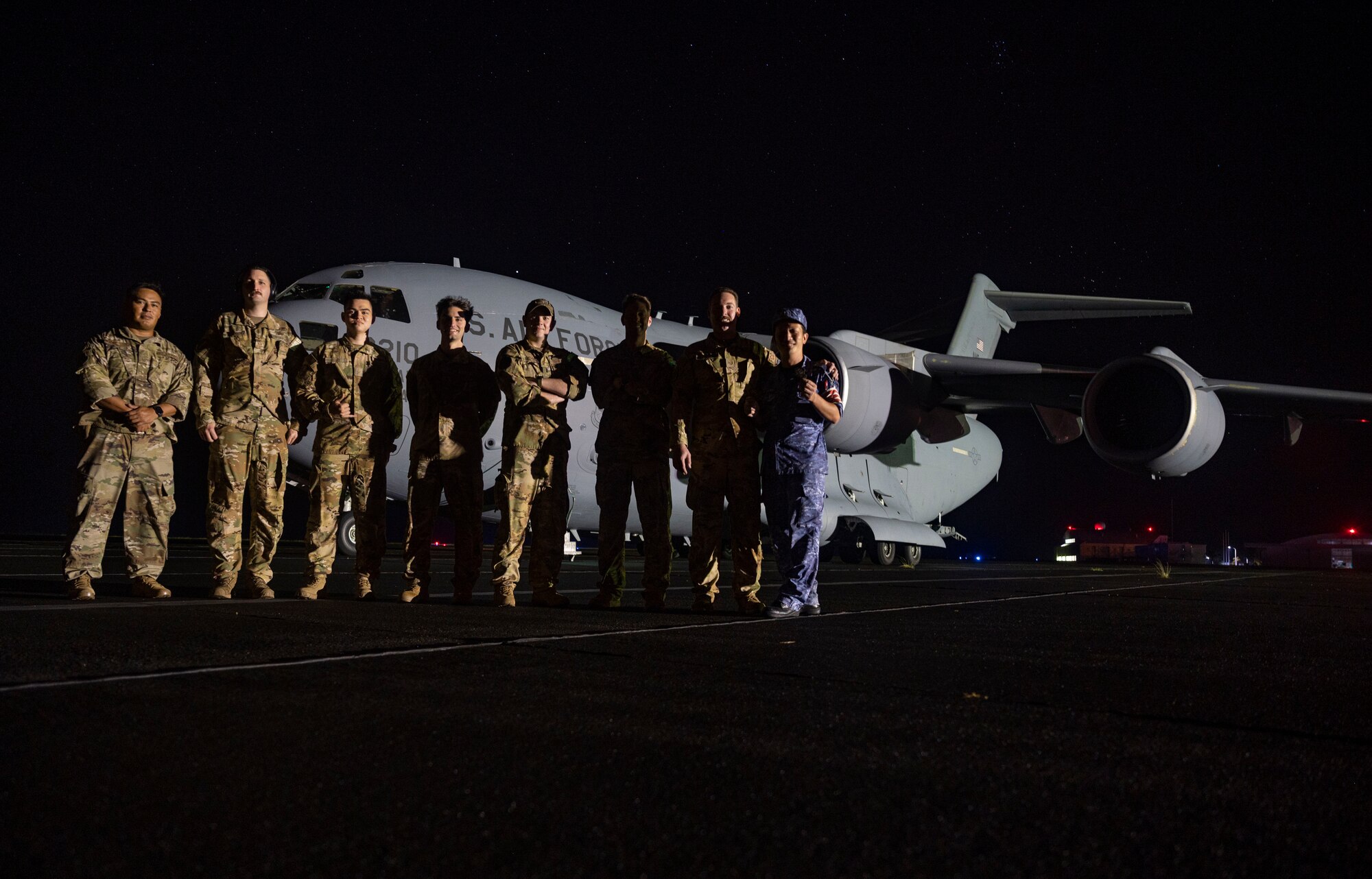 An aircrew with the 7th Airlift Squadron, Joint Base Lewis-McChord, Washington, and a member of the Japanese Self Defense Air Force, pose for a photo in front of a C-17 Globemaster III in Iwo Jima, Japan, during Exercise Rainier War 21B, Nov. 7, 2021. Rainier War 21B exercises and evaluates the 62nd Airlift Wing’s ability to employ the force and their ability to perform during wartime and contingency taskings in a high-intensity, wartime contested, degraded and operationally limited environment while supporting the contingency operations against a near-peer adversary in the U.S. Indo-Pacific Command area of responsibility. (U.S. Air Force photo by Staff Sgt. Rachel Williams)