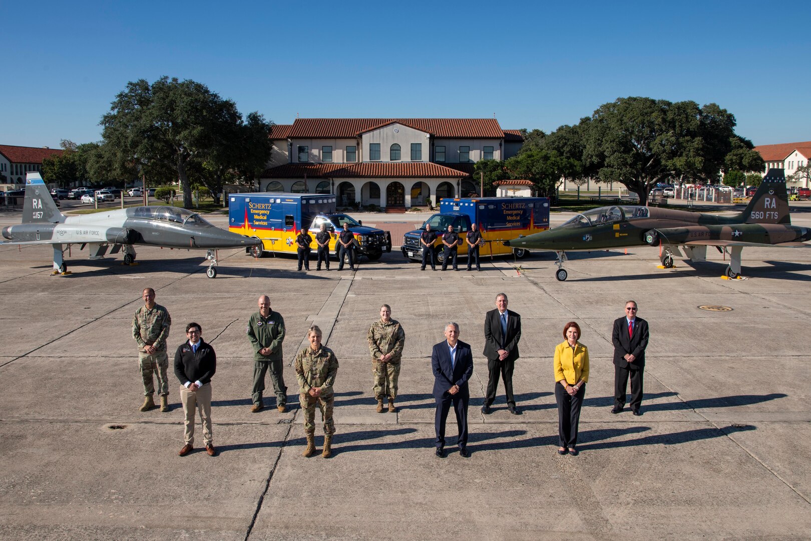 People standing in front of aircraft and ambulances.