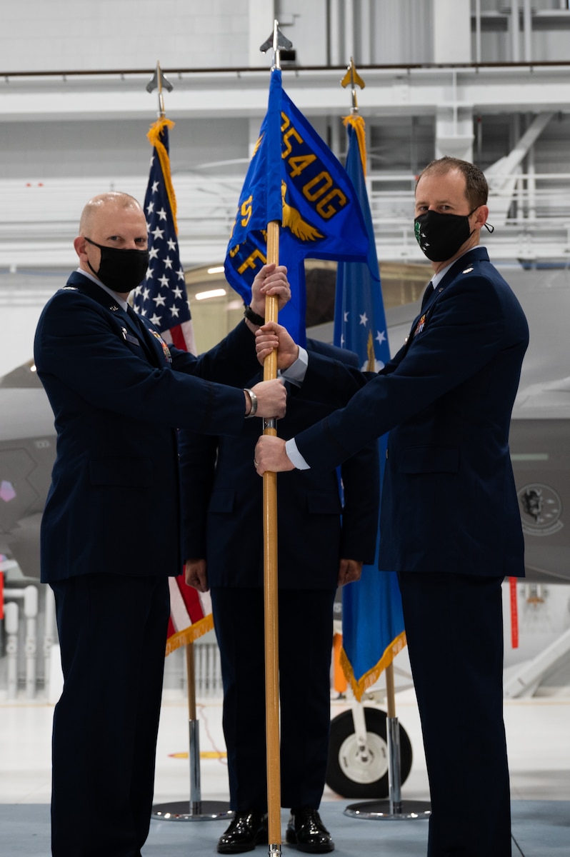 U.S. Air Force Col. Lawrence Evert, the 354th Operations Group commander (left), passes the 356th Fighter Squadron (FS) guidon to Lt. Col. Ryan Worrell, the 356th FS  commander, during a change of command ceremony on Eielson Air Force Base, Alaska, Nov. 5, 2021.
