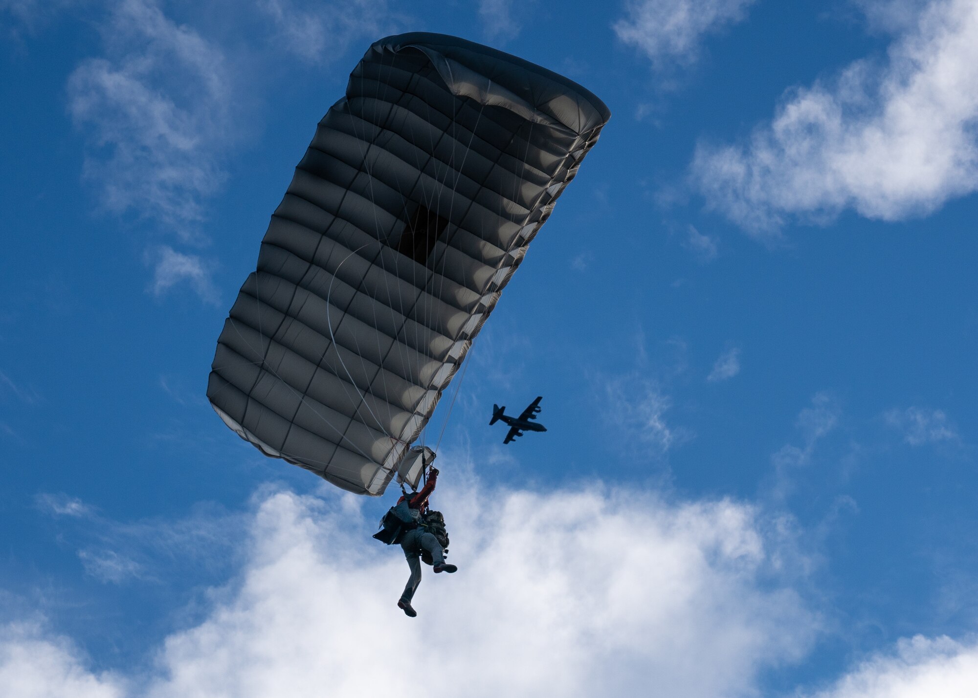 U.S. Air Force Tech. Sgt. Tyler Albee, a pararescueman assigned to the 212th Rescue Squadron, Alaska Air National Guard, glides beneath an Alaska Air National Guard HC-130J Combat King II operated by an aircrew from the 211th Rescue Squadron during a training event at Joint Base Elmendorf-Richardson.