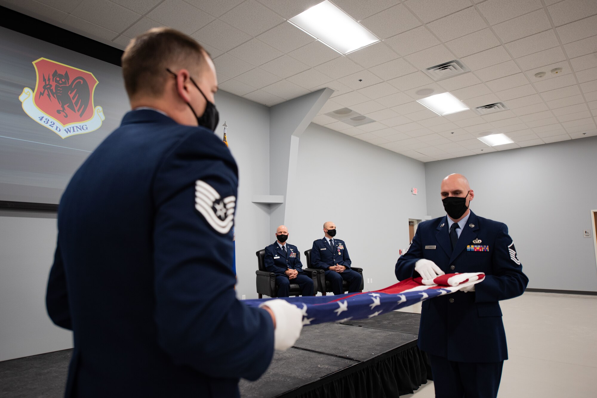 Two Airmen fold a flag during Maj. Matthew Mendenhall's retirement ceremony.