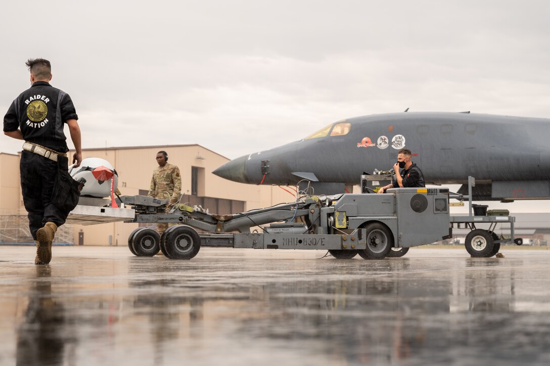 Airman 1st Class AJ Barkalow, 37th Aircraft Maintenance Unit load crew member, right, drives an MHU-83D/E while transferring munitions at Ellsworth Air Force Base, S.D., Sept. 13, 2021. No matter the weather, Ellsworth Airmen remain focused on any task at hand and are always ready for the fight. (U.S. Air Force photo by Senior Airman Michael Ward)