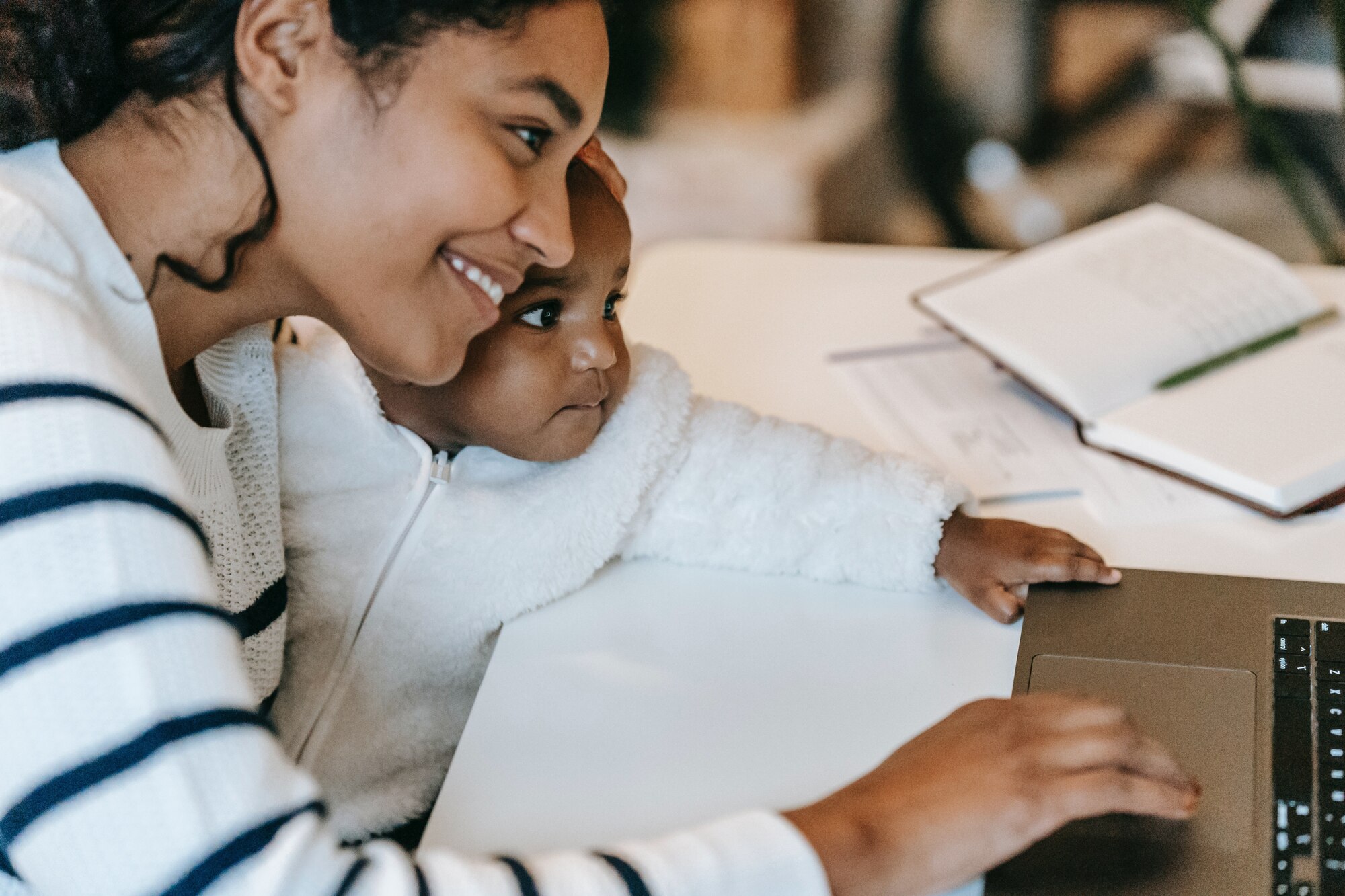Mom holds baby while on laptop