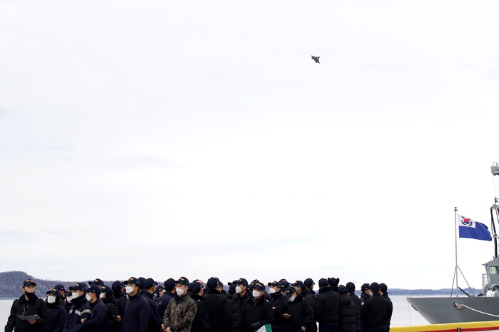 Midshipmen from the Republic of Korea Navy (ROKN) Cruise Training Task Group’s two vessels, a Republic of Korea Ship (ROKS) Wang Geon (DDH-978) Chungmugyon Yi Sun-sin-sin-class destroyer and ROKS So Yan (AOE-51), a combat support ship, watch as an F-22 Raptors passes by at the Port of Alaska, Anchorage, Nov. 4, 2021. The ROKN Cruise Training Task Group visited Alaska during a 67-day voyage, which marked the first ever trip for ROKN vessels to the state.(U.S. Air Force photo by Sheila deVera)