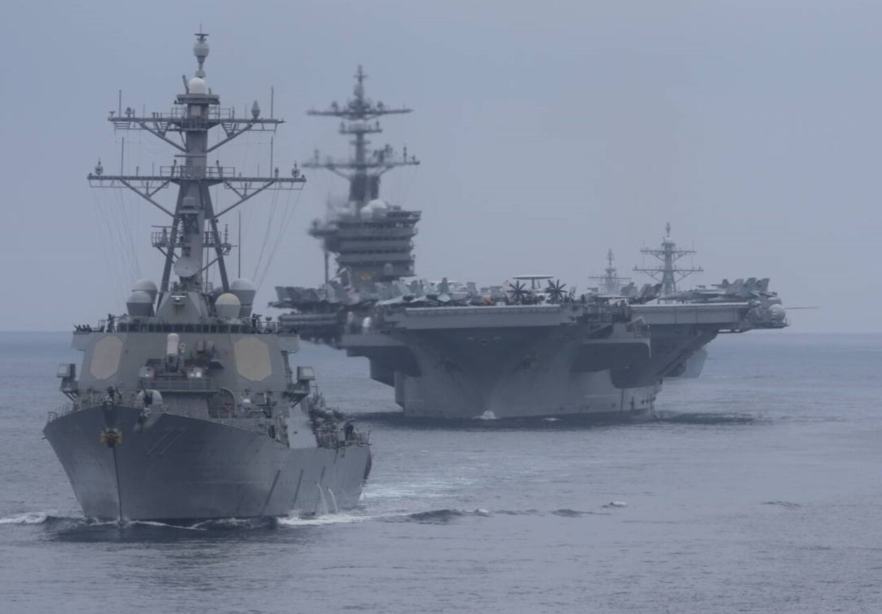 Large military ships move through the ocean.