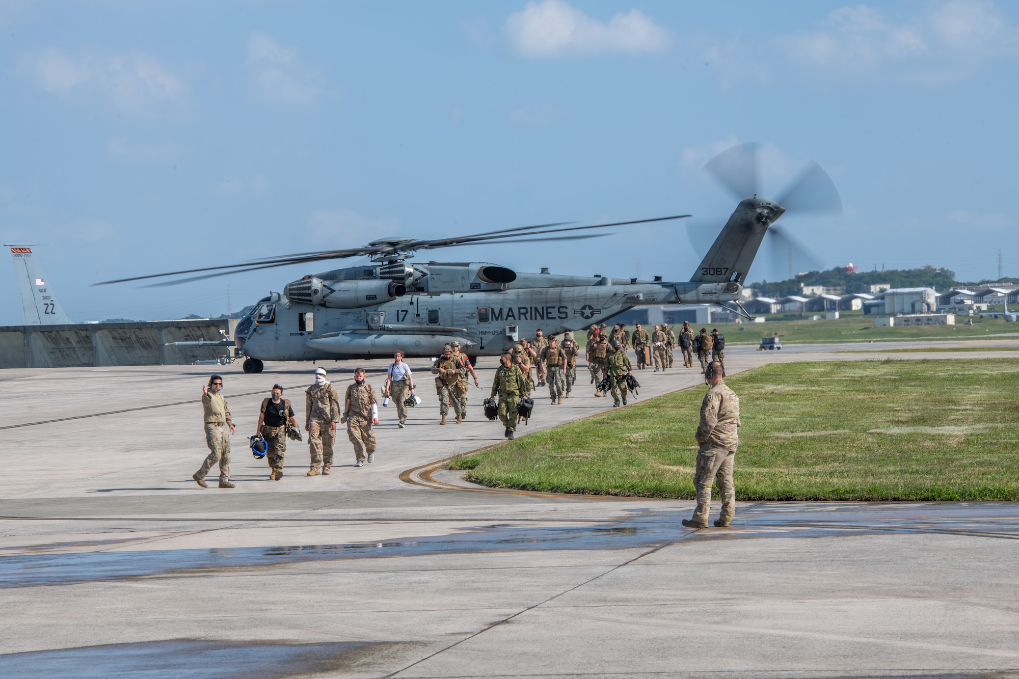 A bunch of military personnel walk away from a helicopter on the flight line