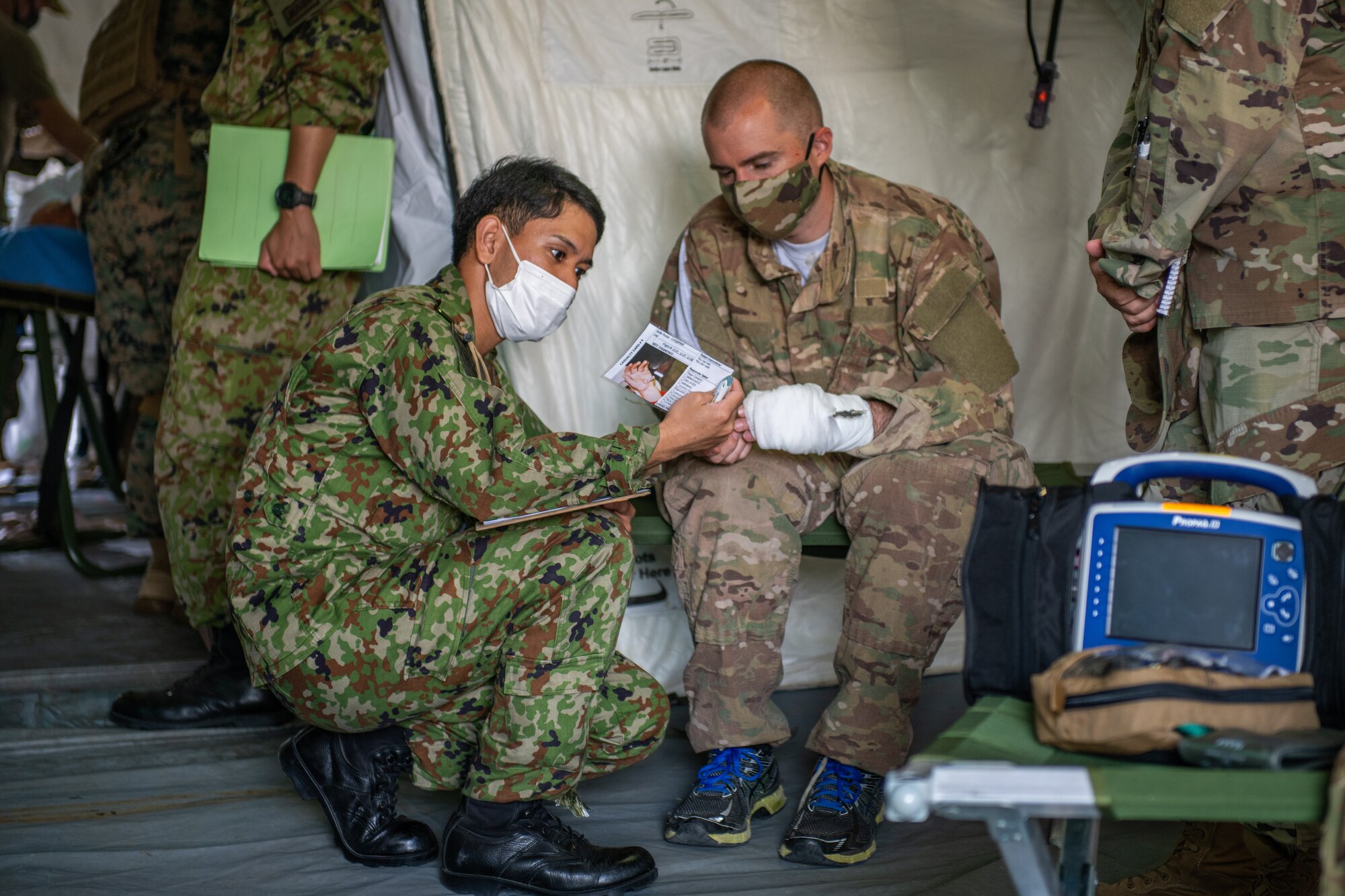 A Japanese military personnel attends to a U.S. Air Force member roleplaying a patient