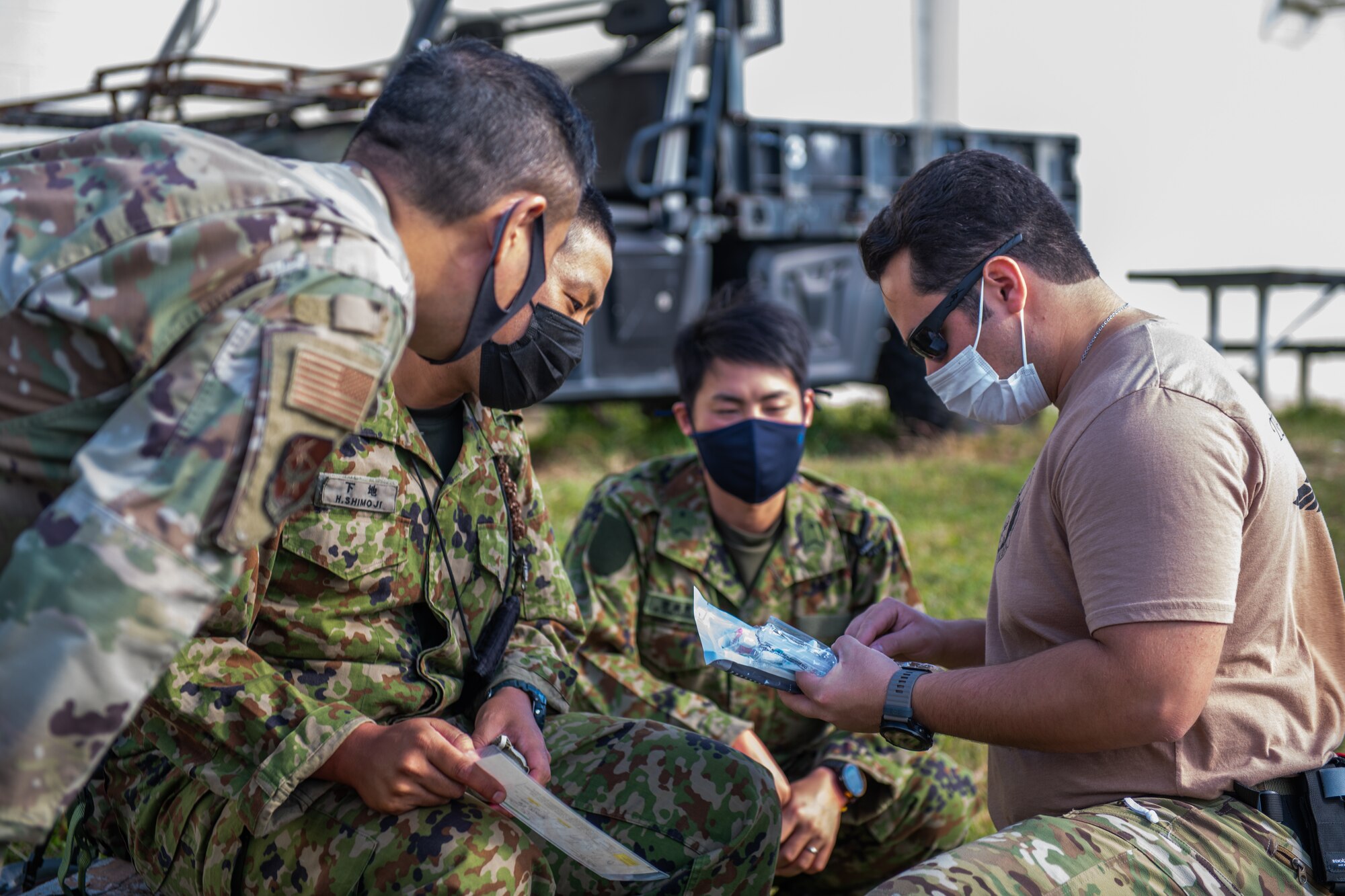 Two Japanese military members roleplaying patients are attended by two American military members