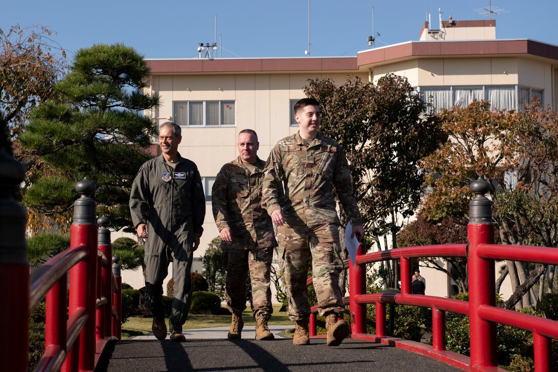 An AFN airman escorts two high ranking officials into a Japanese garden.