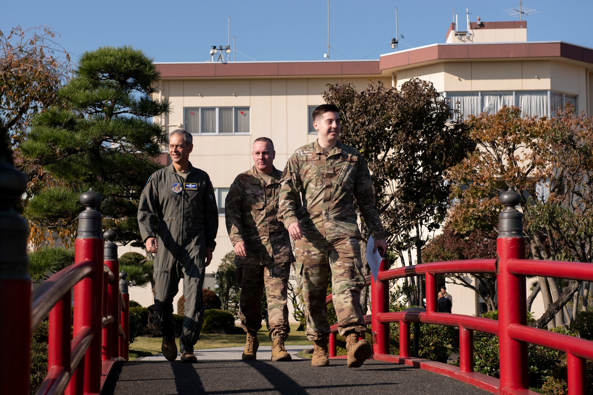 An AFN airman escorts two high ranking officials into a Japanese garden.