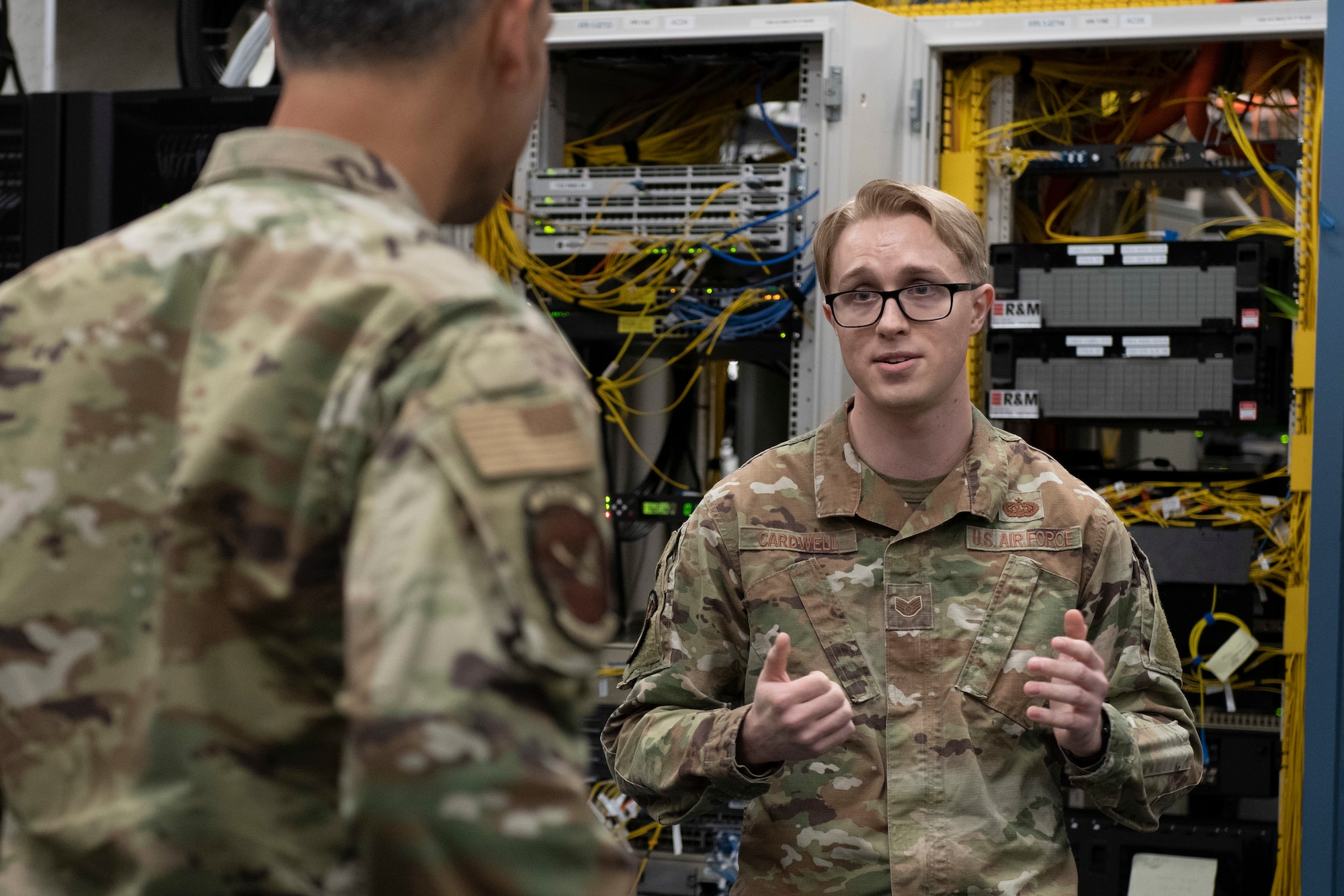 Pacific Air Forces General is briefed by a Sergeant in front of banks of computer servers.