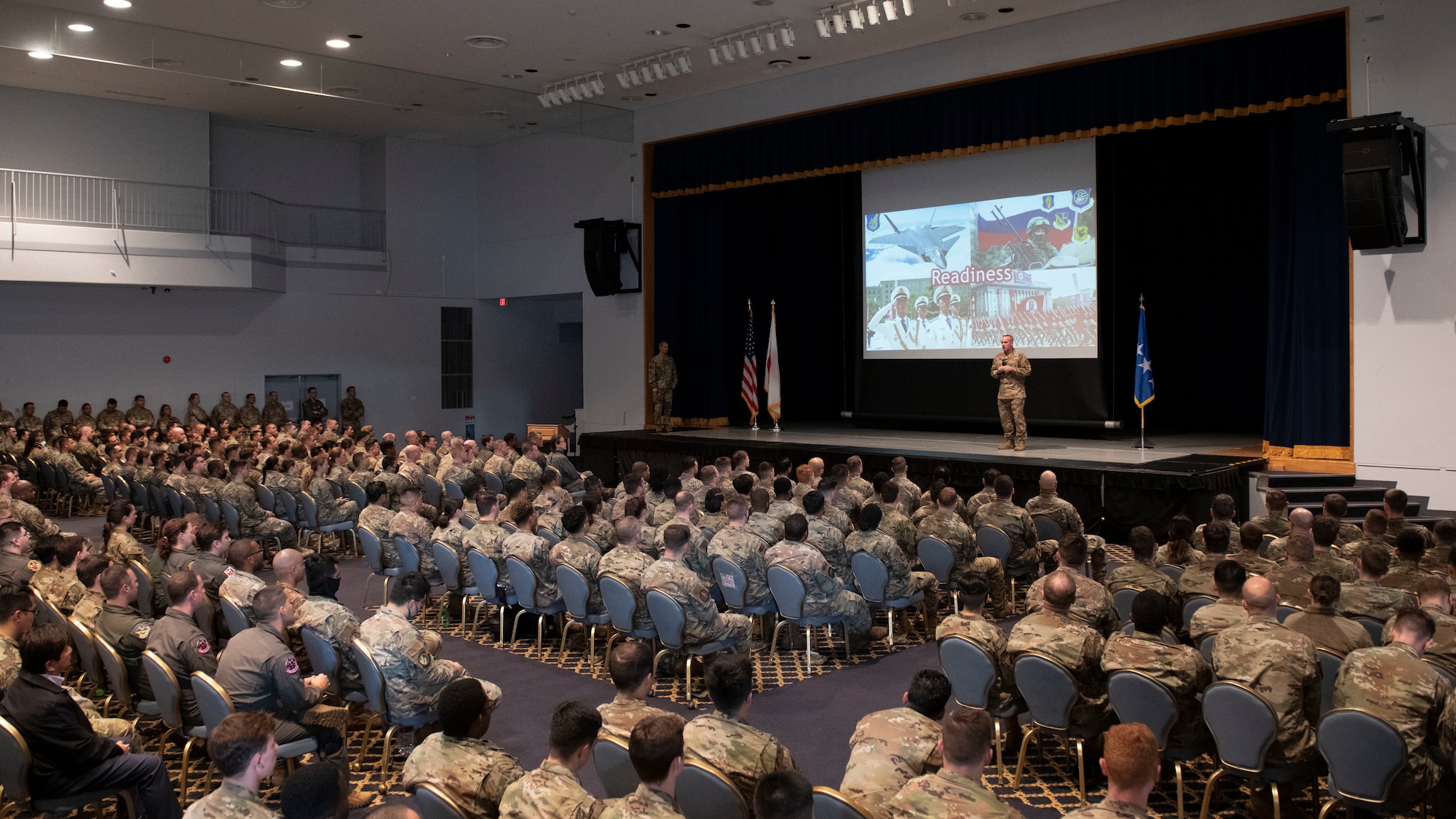Hundreds of UASF Airmen seated in a large auditorium listen to a visiting General.