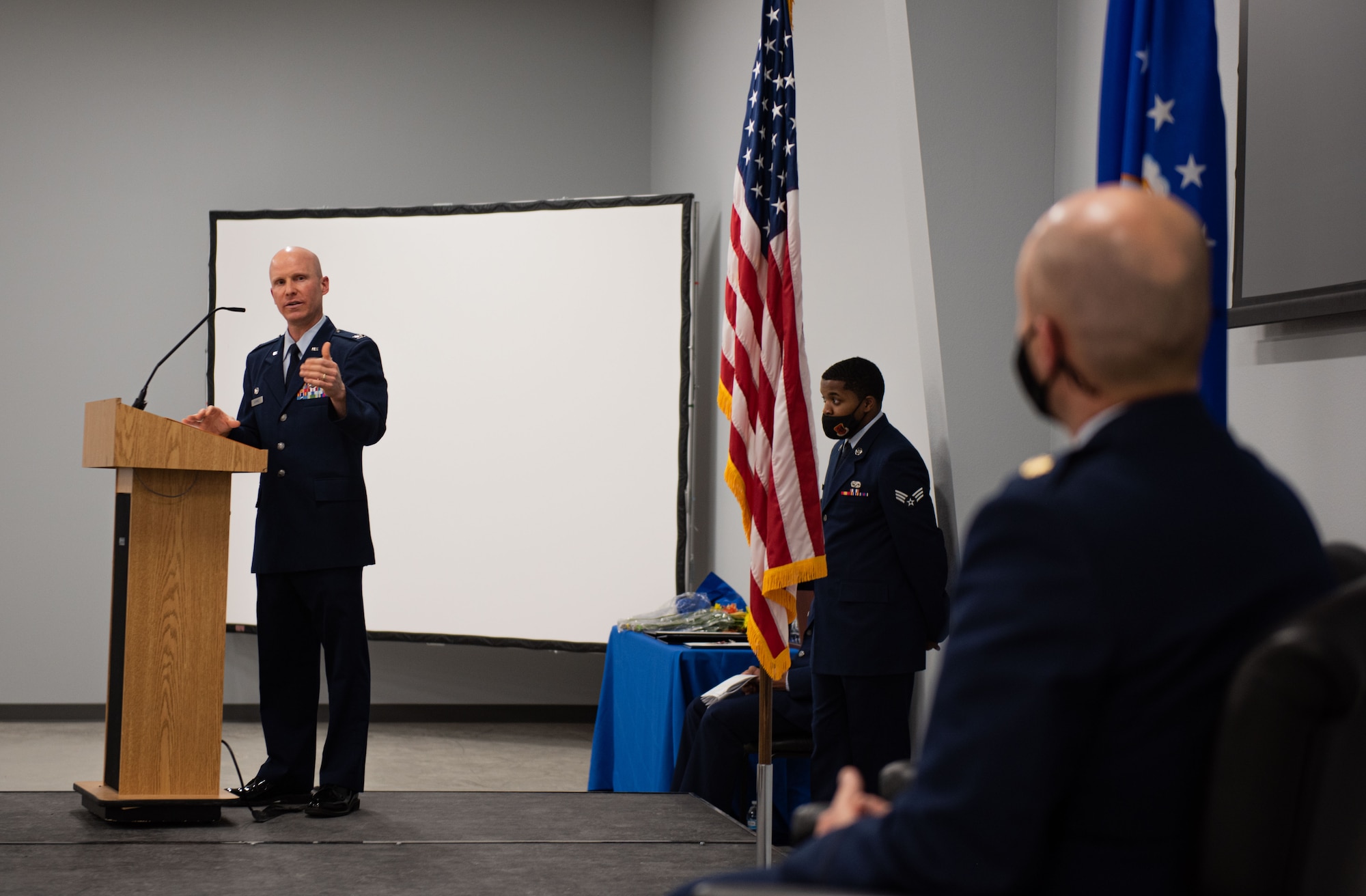 Col. Eric Schmidt speaks on the stage at Maj. Matthew Mendenhall's retirement ceremony.