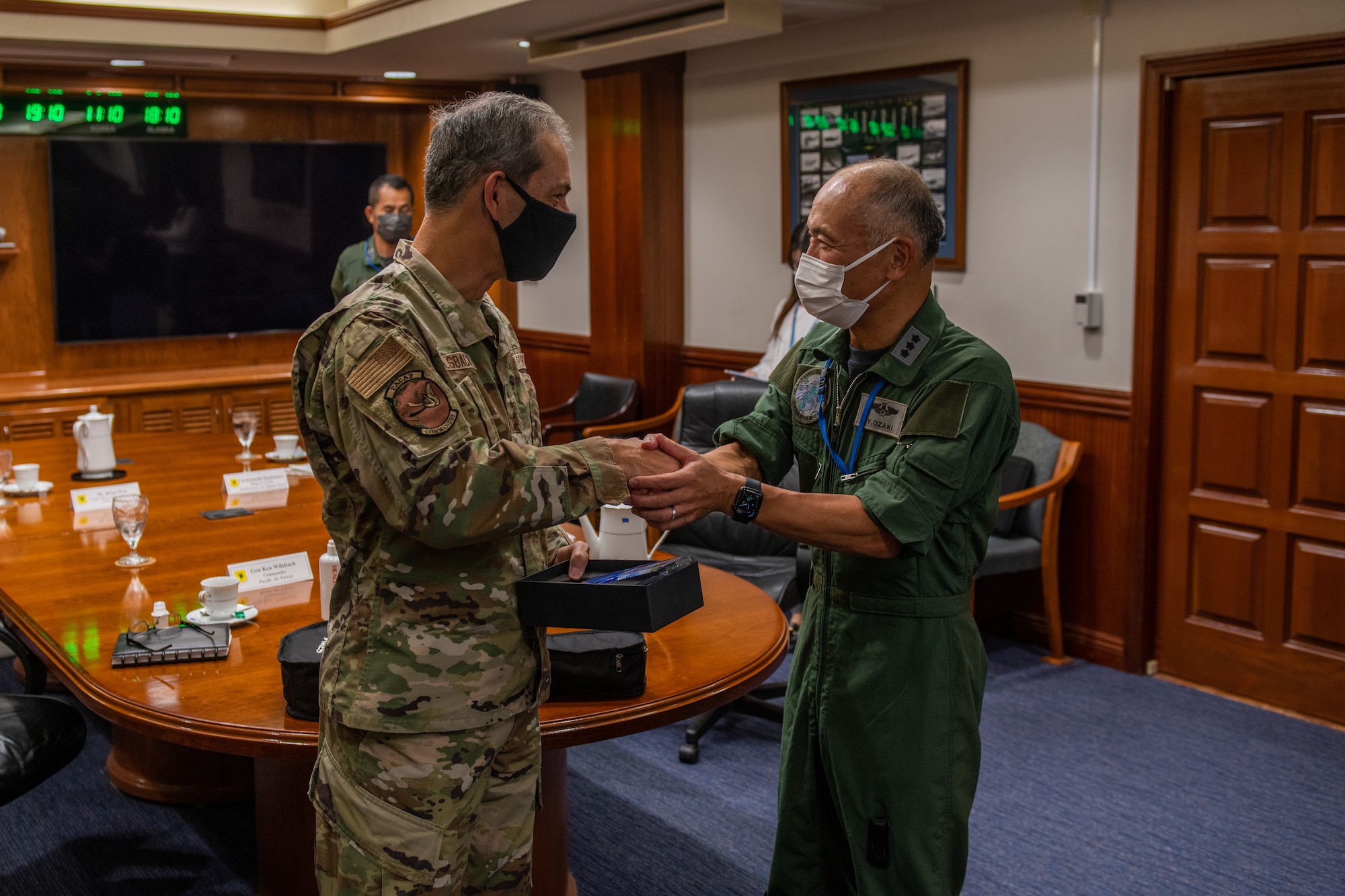 A U.S. Air Force General shakes hands with a Japanese Lieutenant General in a meeting room