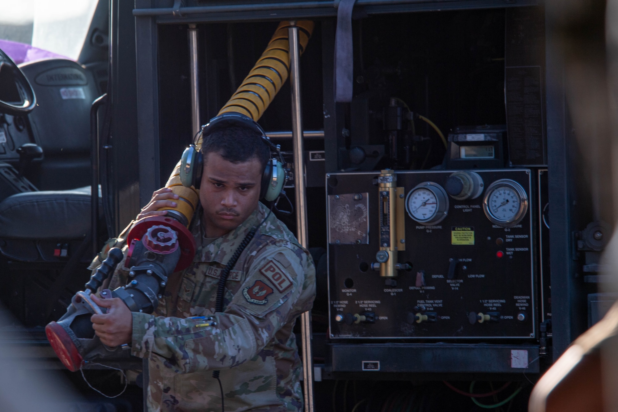 a fuels distribution operator pulls a fuel pump hose during an Agile Combat Employment training event