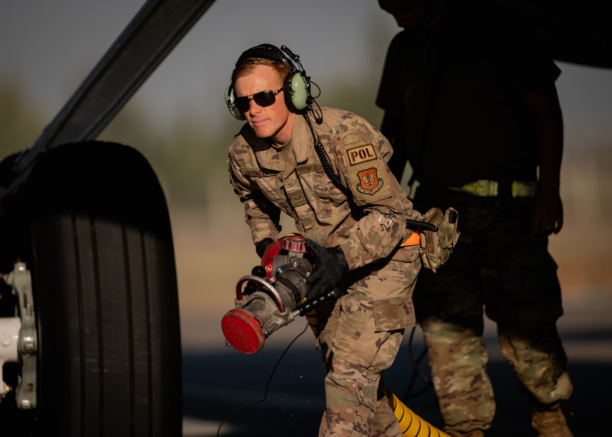 a fuels distribution operator carries a fuel hose after refueling a KC-135 Stratotanker