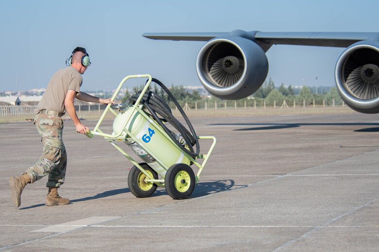 U.S. Air Force crew chief wheels fire extinguisher to KC-135 Stratotanker