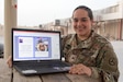 Sgt. Naslie I. Hutchins, a human resources specialist assigned to the Fort Bragg, N.C., based 3rd Expeditionary Sustainment Command, poses with some of the graphic designs she created for a cookbook she independently published on Oct. 24, 2021, from Camp Arifjan, Kuwait. The Soldier said she wrote the cookbook to both honor her Hispanic heritage and to preserve it for her sons.