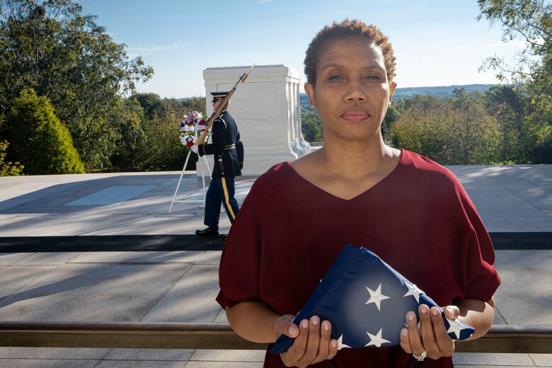 U.S. Navy Veteran Tina Holmes, U.S. Army Corps of Engineers, Baltimore District, Equal Employment Opportunity specialist, holds a U.S. flag while a Sentinel performs a Changing of the Guard demonstration at the Arlington National Cemetery’s Tomb of the Unknown Soldier in Arlington, Va., Oct. 22, 2021. The Army initially dedicated the Tomb on Armistice Day, Nov. 11, 1921, with the burial of an unknown service member from World War I. Over the past century, additional unknowns have been buried at the Tomb, and the site has become a people’s memorial that inspires reflection on service, valor, sacrifice, and mourning. (U.S. Army photo by Greg Nash)