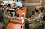 Airman Roxana Horjescu, 802nd Force Support Squadron customer support technician, left, hands a Space Force ID card to Lt. Col. Michael Graff