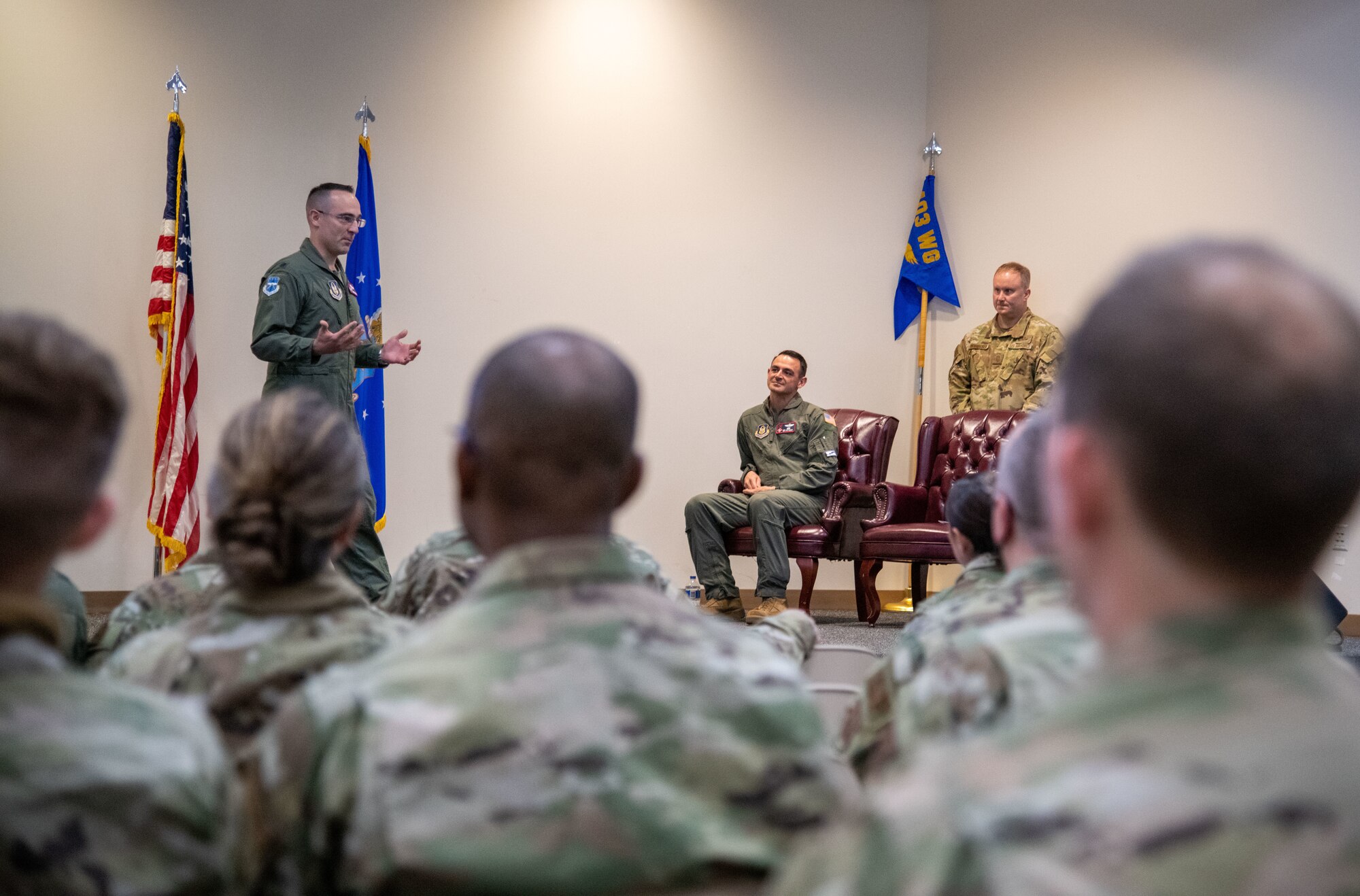 Airmen in the foreground look on as Campanile speaks. Rubio sits in a chair to the right listening.