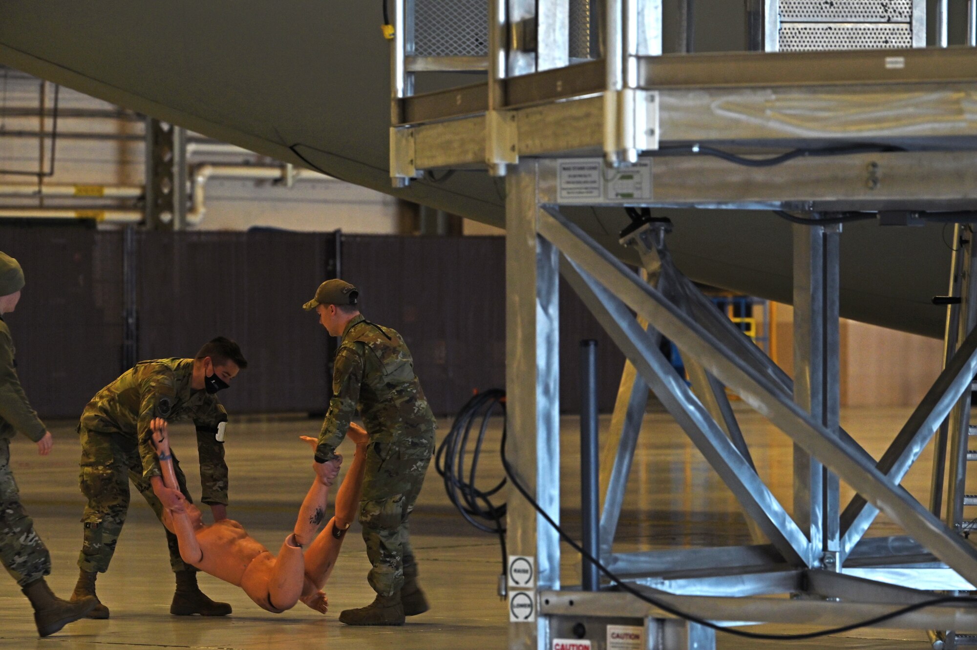 62nd Maintenance Squadron Airmen place a simulated victim inside a hangar before a simulated emergency incident during Exercise Rainier War 21B at Joint Base Lewis-McChord, Washington. Rainier War is a semi-annual, large readiness exercise led by 62nd Airlift Wing, designed to train Airmen under realistic scenarios that support a full spectrum readiness operations against modern threats and replicate today’s contingency operations.  (U.S. Air Force photo by Senior Airman Zoe Thacker)